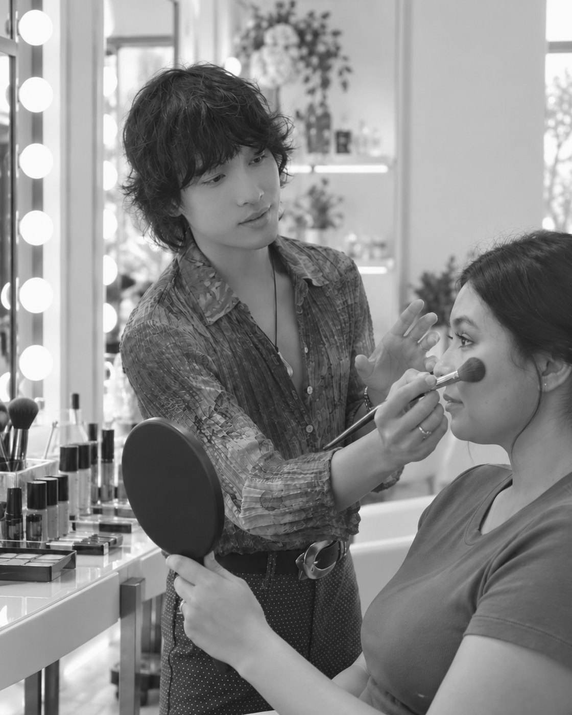 Xander Tang teaching a private makeup lesson, applying blush at a lit vanity in a Los Angeles studio