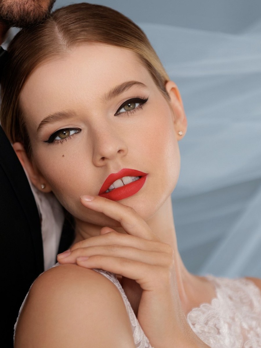 Studio bridal makeup by Xander Tang, bold red lip and winged liner, editorial blue backdrop
